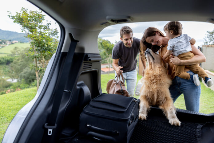 Happy family loading bags in the car and going on a road trip